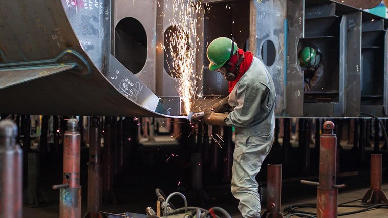 A man welding inside a shipbuilding factory - stock photo