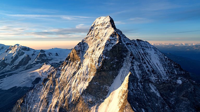 A snow covered mountain peak against a blue sky.