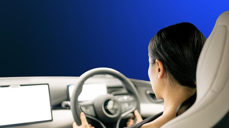 An Asian woman sits in the cockpit of a new energy car, operating a display with intelligent driving functions
