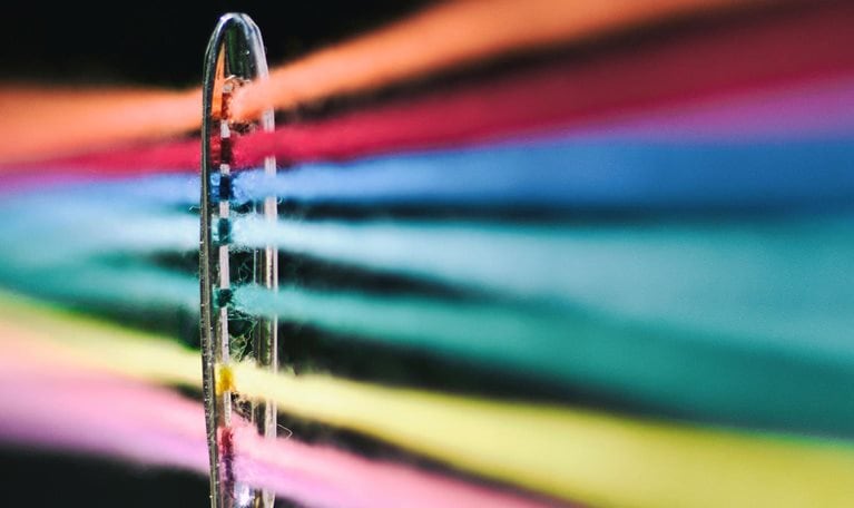 Needle of sewing and its colored threads - stock photo
