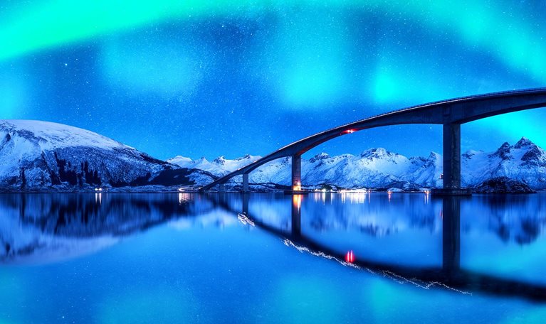 A Bridge and aurora borealis over snowy mountains