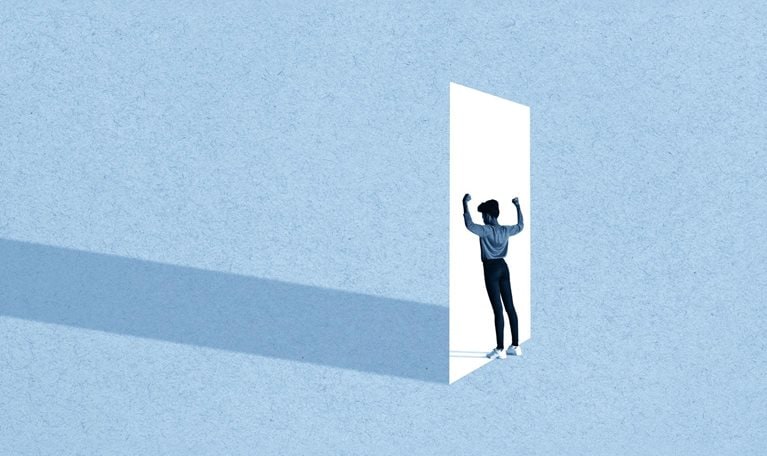 Full length of young woman flexing muscles while standing in front of white doorway against blue background