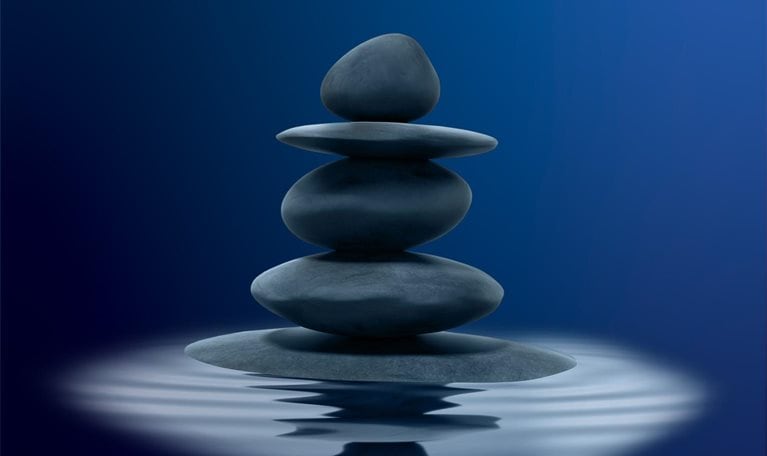 Stacked black zen stones in shallow water