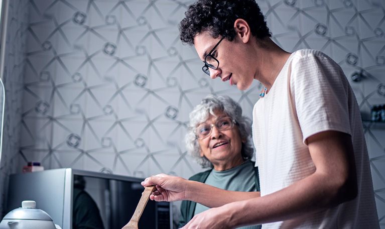 Image of a grandson and grandmother cooking together at home.