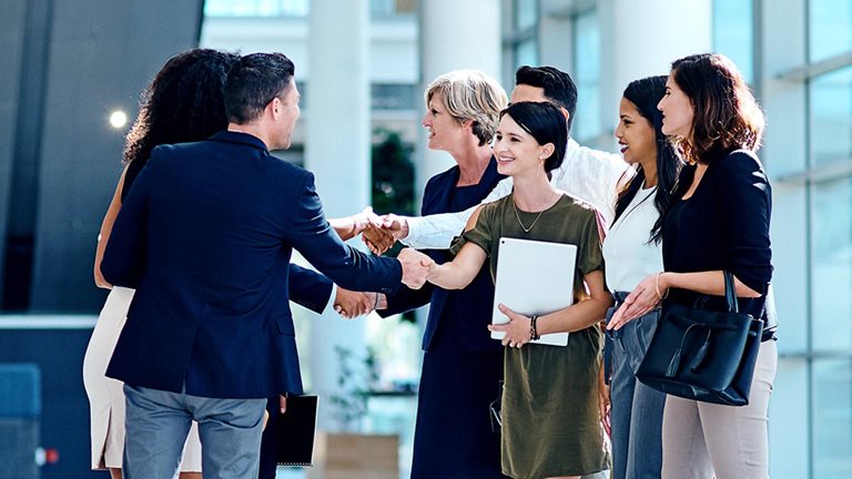 Image of a group of businesspeople greeting each other inside of a office
