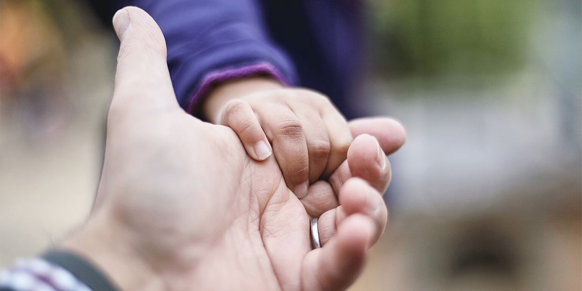 A photo of a man holding a child's hand