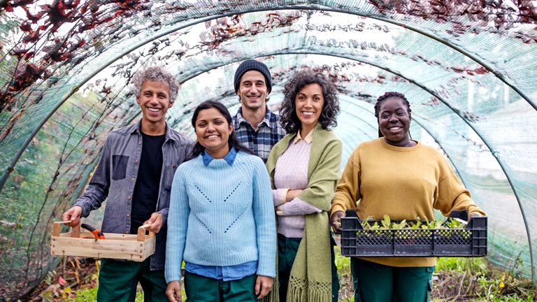Group portrait of garden center workers standing together with plant crates
