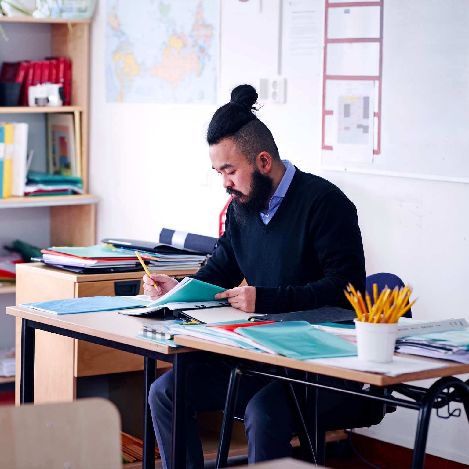 Image of a teacher working at a desk in a school