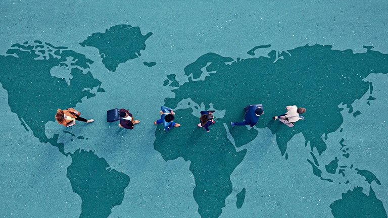 Image of businesspeople walking in line across world map painted on asphalt