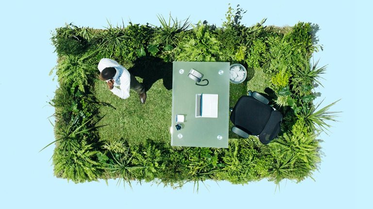 Image of businessman and desk on lush lawn in cement courtyard