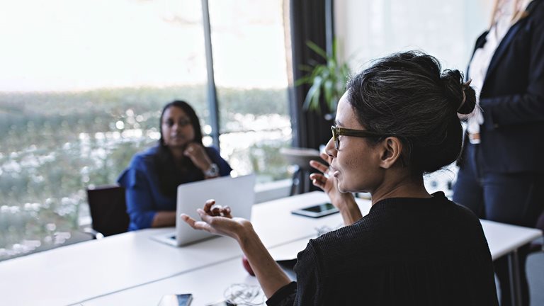 Businesswoman gesturing while in discussion with colleagues