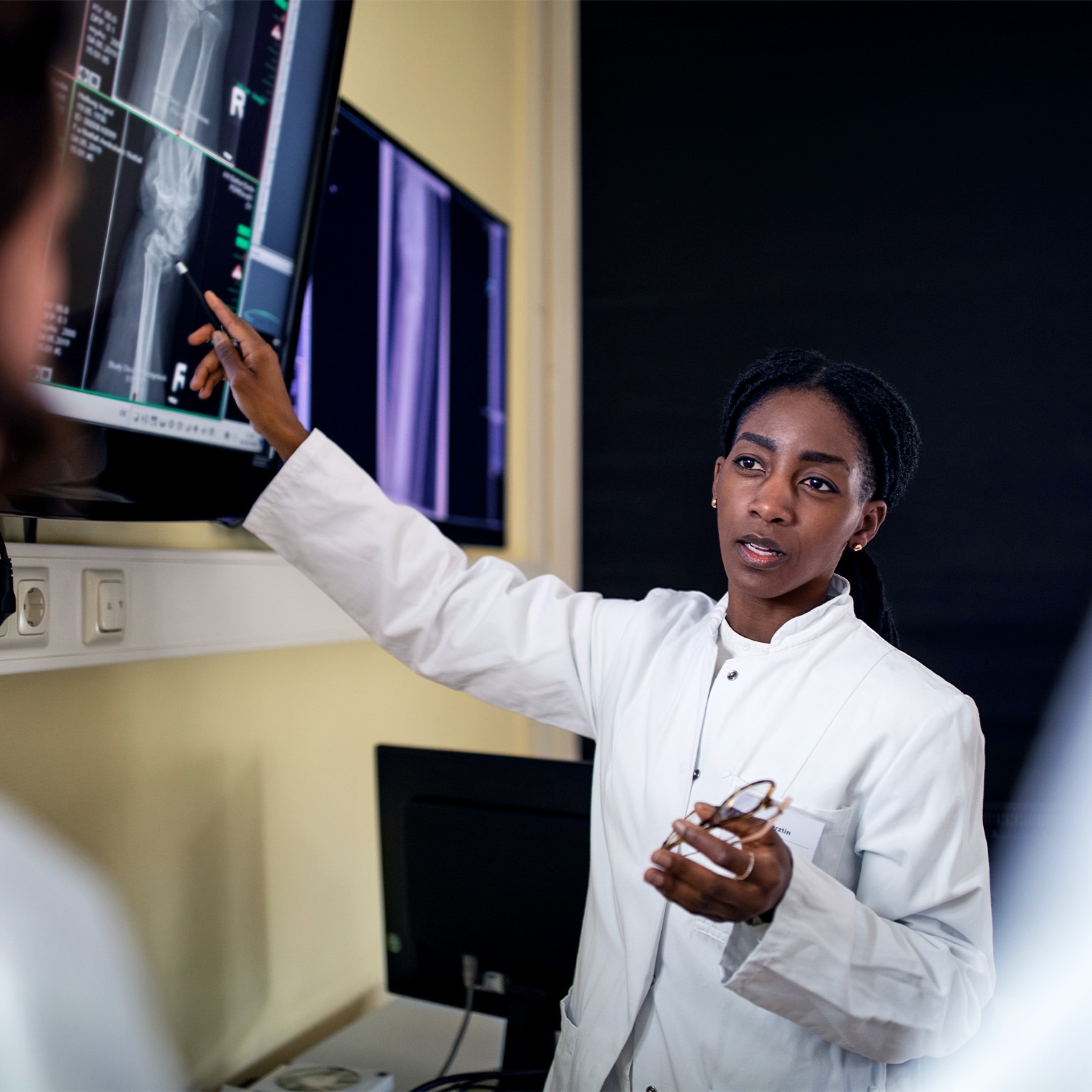 Image of a female surgeon discussing patient's scan and diagnosis with colleagues