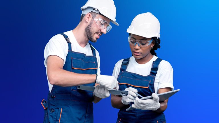 Image of two workers in hardhats and overalls in front of a blue backdrop