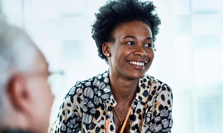 Cheerful woman in her 30s in business meeting with colleagues, smiling and listening, confidence, expertise, team player