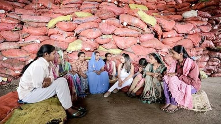 Shrankhla speaks with several of her women employees surrounded by cloth sacks of herbs