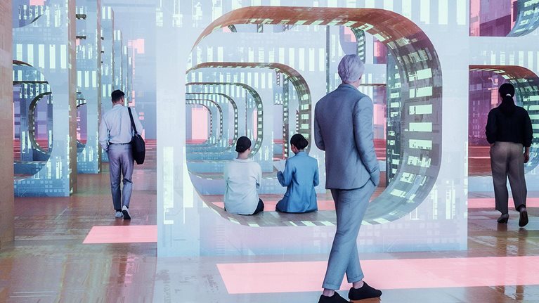 An image of a futuristic environment, with people walking and sitting among large, glowing geometric structures that serve as portals to digital structures.