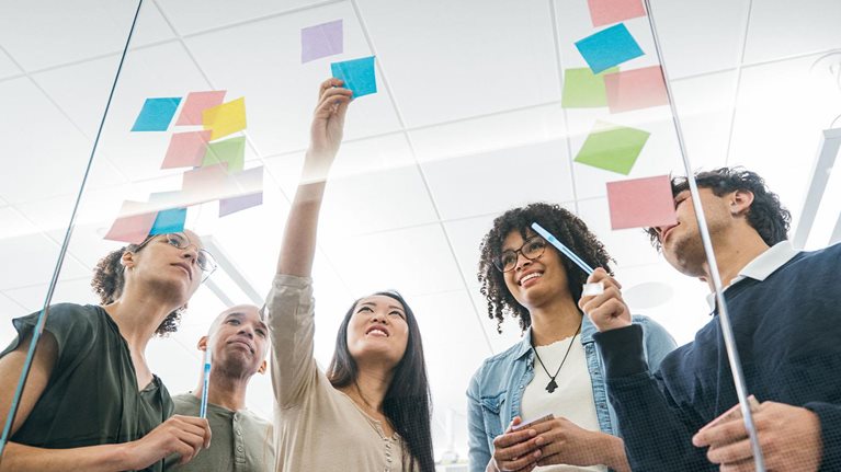 Business team brainstorming with sticky notes on glass wall