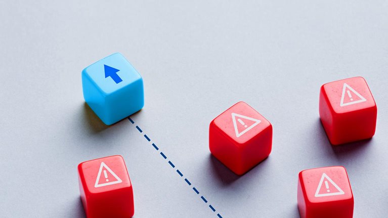 A blue cube, marked with an upward arrow, moves along a dotted path, navigating through a group of red cubes that are marked with warning symbols.