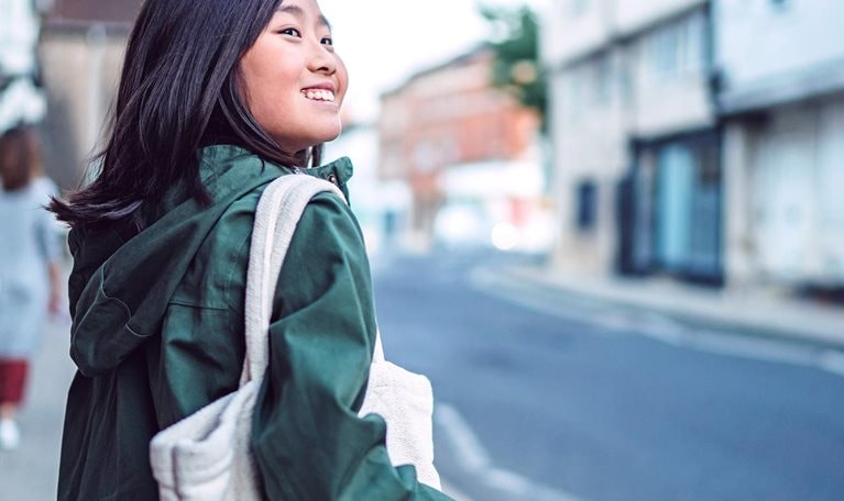 Cheerful teenage girl walking in the street while exploring in a town