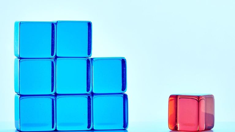 An incomplete blue square shape with one red cube standing apart