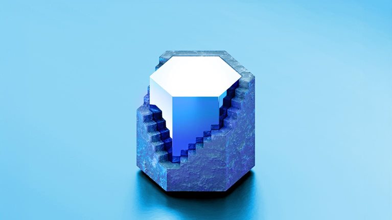 A geometric blue hexagon featuring a rocky outer surface, with a section removed to expose a polished, luminous gemstone at its center. The structure sits on a glossy blue surface against a soft blue background, giving it a clean, modern, and abstract feel.