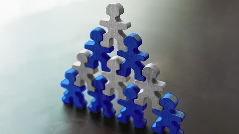 Wooden human figures forming a pyramid symbolizing teamwork, leadership, support, and organizational success. Concept of collaboration, unity, human resources, and business development.