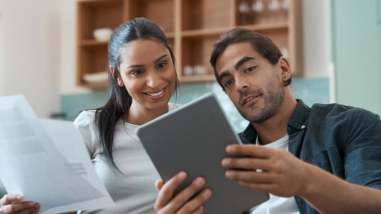 Shot of a young couple doing paperwork while using a digital tablet at home