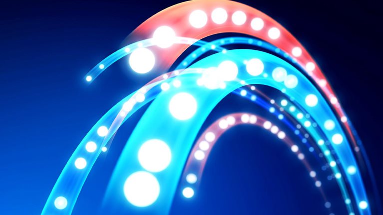 An abstract close-up of glowing curved light trails in bright cyan, blue, white, and coral against a dark background.