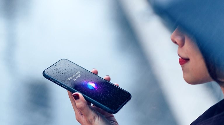 Image of a woman using voice assistant on smartphone in the rain.