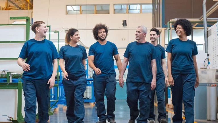 Front view of group of blue-collar workers walking in factory.