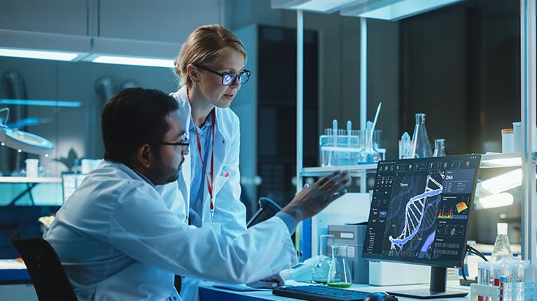 Female Research Scientist with Bioengineer Working on a Personal Computer with Screen Showing DNA Analysis Software User Interface. Scientists Developing Vaccine, Drugs and Antibiotics in Laboratory