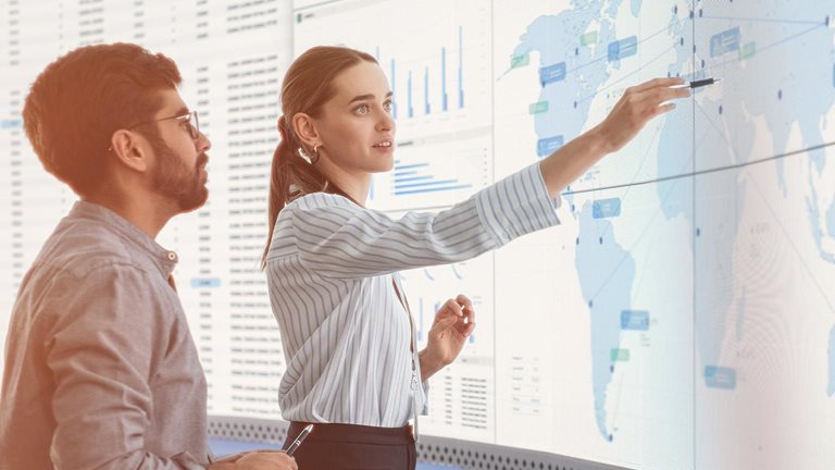 Diverse colleagues, data scientist and business manager, discussing objectives talking in front of big digital screen with graphs, charts and map in monitoring office. - stock photo