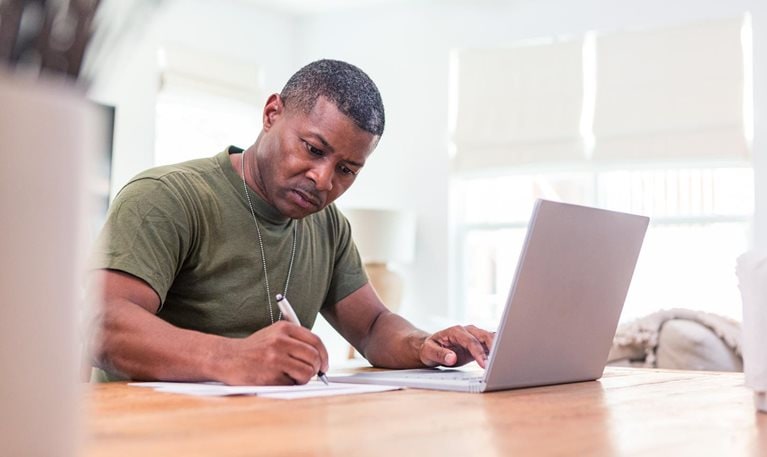 Serious mature adult soldier takes continuing education courses online using his laptop.