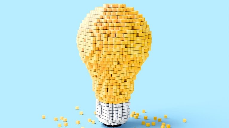 Light bulb shape made of small yellow cubes on a blue background.
