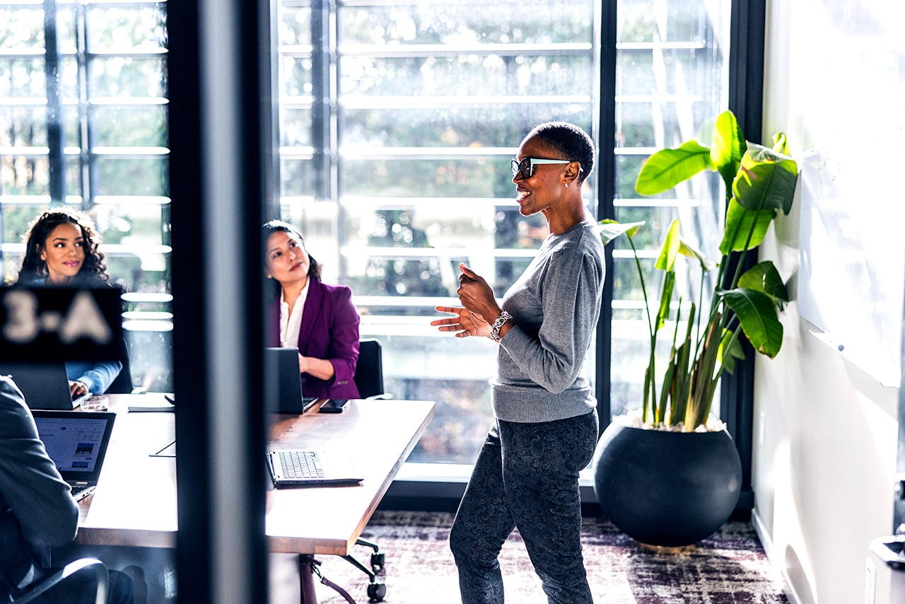 Three professional women in an office during a small group presentation.