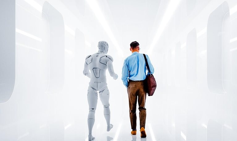 A man dressed in business-casual attire walks side by side with a humanoid robot down a futuristic corridor. The pair are viewed from behind, walking away from the viewer into the brightly lit space.