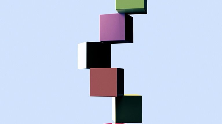 A set of colorful cubes arranged in a precarious stack, teetering on the edge of a surface.