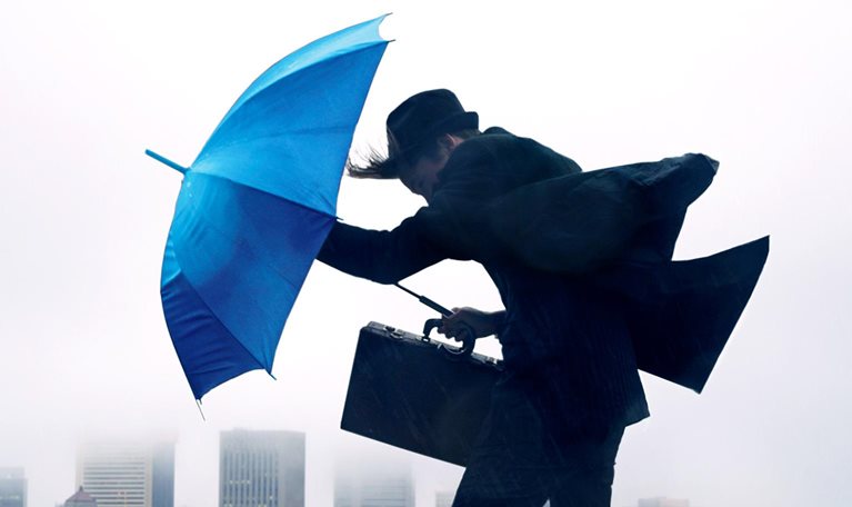 Businessman with umbrella in the wind