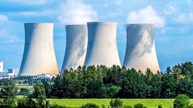 Nuclear power plant with trees and a lush green field in front of it