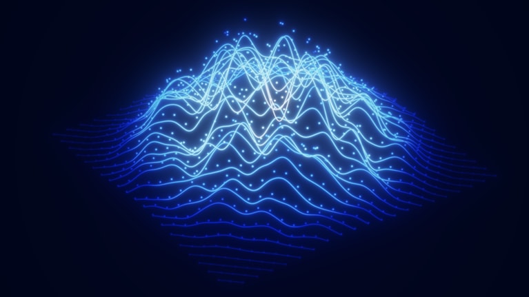 This image is a digital rendering of a futuristic wireframe landscape often used to visualize big data or sound waves. It features glowing blue lines forming hilly terrain, resembling mountains or wave patterns on a dark background. Small, scattered dots are embedded along the light trails to represent data points or particles.