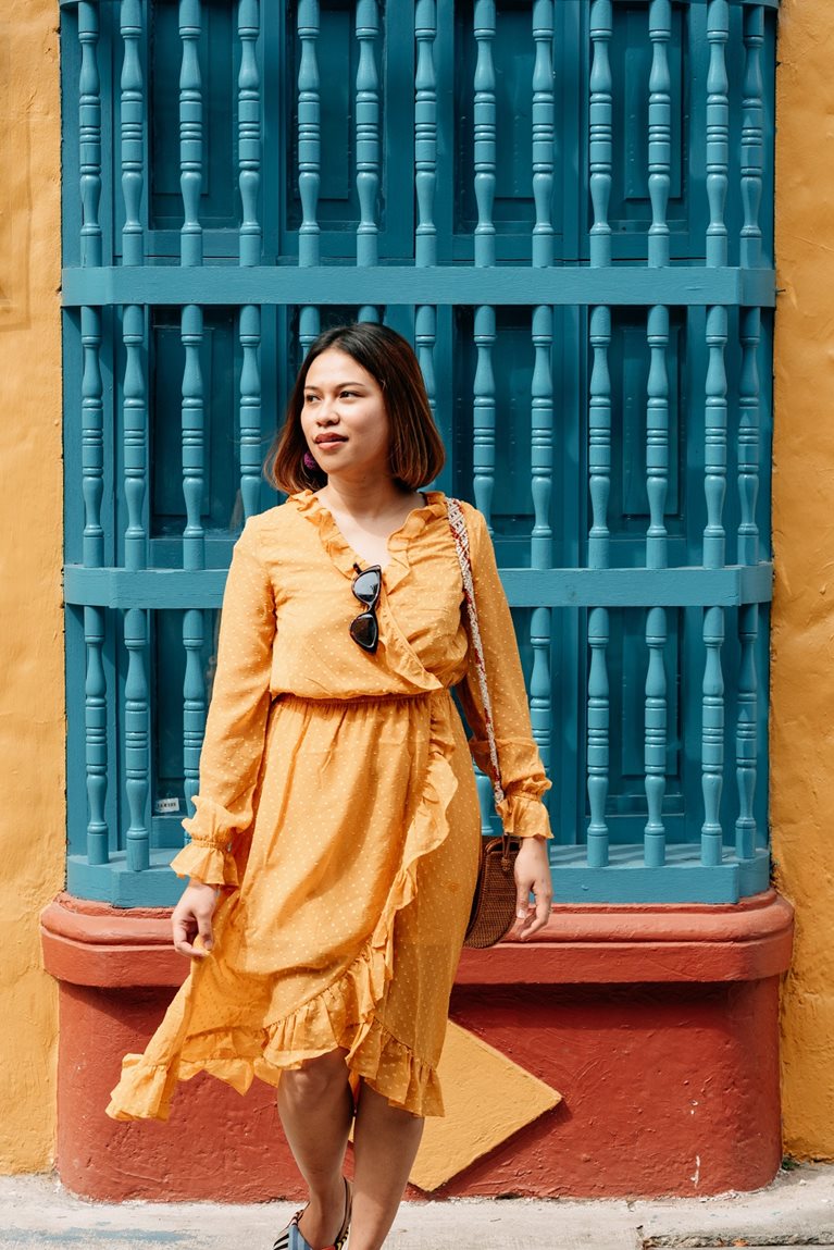 Winny in orange dress outside of colorful building