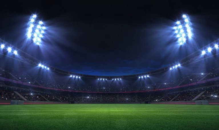 Universal grass stadium illuminated by spotlights and empty green grass playground