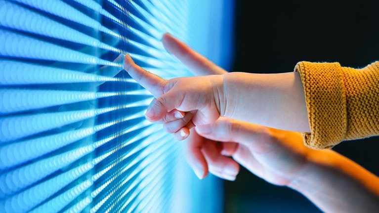 Close-up shot of a mother and kid's hand touching illuminated LED display screen.