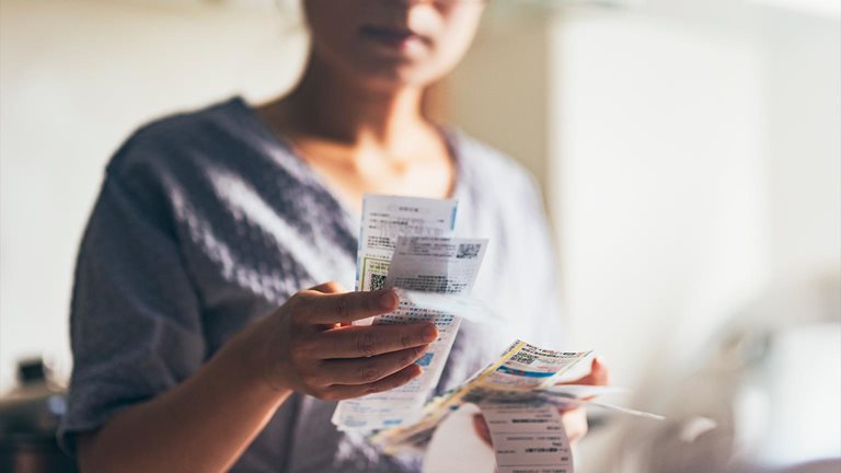 Asian women examining the shopping receipt at home - stock photo