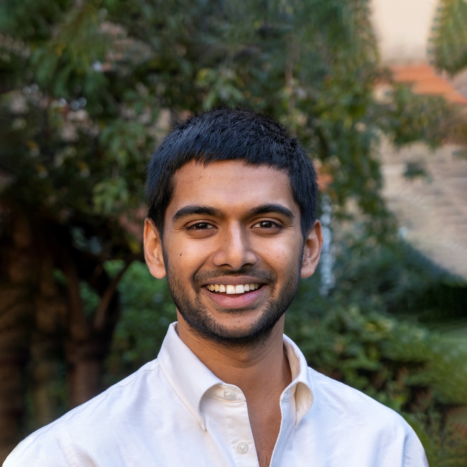 Portrait of a smiling Siddarth Shrikanth against natural greenery