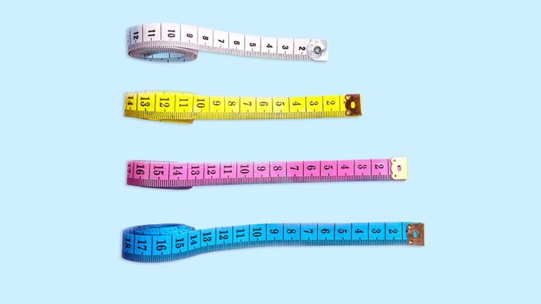 Four measuring tapes are positioned vertically on a light blue backdrop. Each tape is stretched out to varying lengths and placed in increasing order from the longest to the shortest.