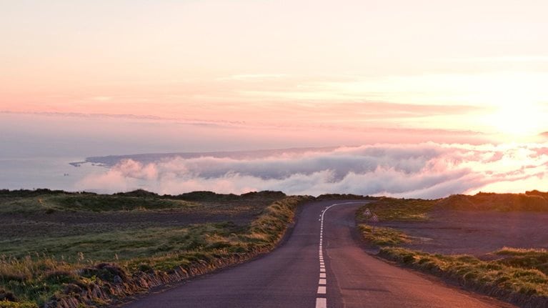 A long country road trailing off into the clouds