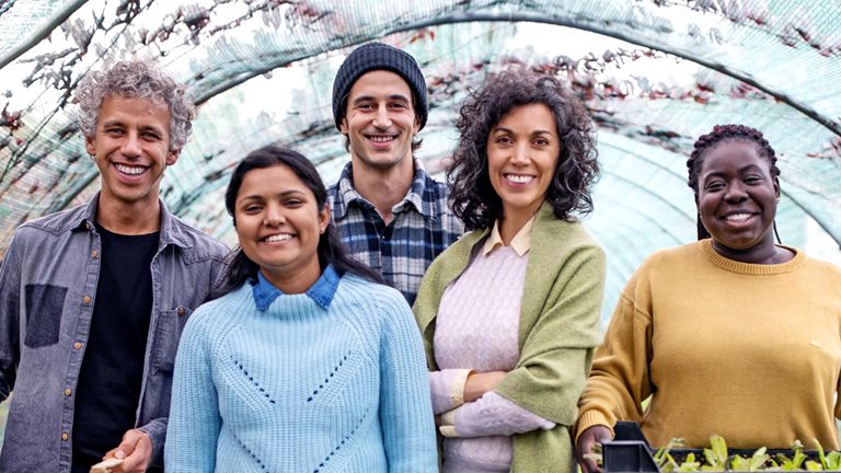 Group portrait of garden center workers standing together with plant crates