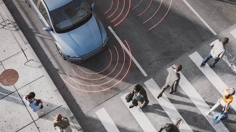 Image of car at an intersection with pedestrians crossing the street