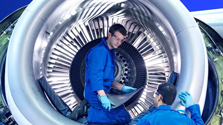 Engineers working with jet engine turbine blade in aircraft maintenance factory